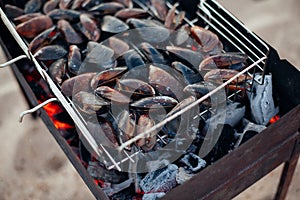 Mussels on the grill.Seafood barbecue outdoors on sand beach.Food and holliday