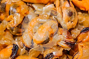 Mussels meat of peeled insides fried with onions in bulk
