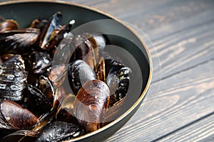 Mussels with parsley and garlic in wog pan on wooden table