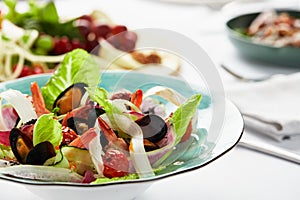 Mussels vongole in a plate with salad, mussels cooked in white wine sauce, on a party table, with white scart, salad