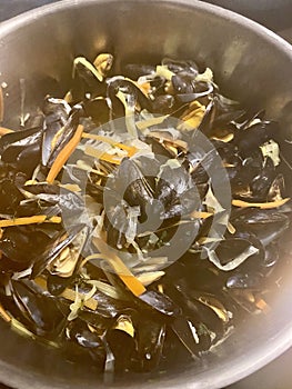 Mussels in white wine steaming and cooking in copper pot - top view