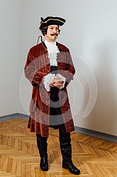 Mustachioed eccentric man in the vintage clothes of the baron. Hat tricorn, brown jacket.