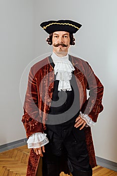 Mustachioed eccentric man in the vintage clothes of the baron. Hat tricorn, brown jacket.