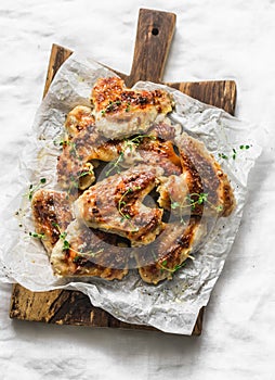 Mustard, lemon, thyme marinade baked chicken wings on wooden chopping board - delicious appetizers, tapas on light background, top