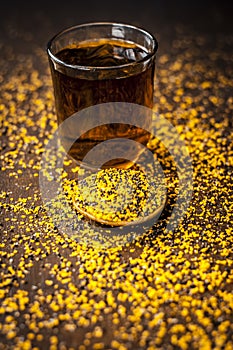 Mustard seed extracted tincture in a glass bowl on wooden surface.