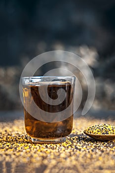 Mustard seed extracted tincture in a glass bowl on wooden surface.