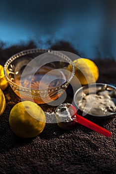 Mustard seed face mask for glowing skin on black surface with raw fresh lemons, mustard seeds, yogurt, honey, and cornflour.