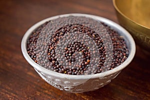 Mustard seeds in a Silver bowl on wooden old Table. Rustic Style