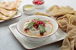 Mutabal with pomegranate seeds and bread served in dish isolated on table top view of arabian food