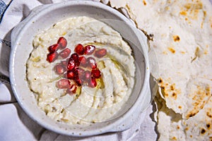 Mutabal with pomegranate seeds, olive oil and pita bread served in dish isolated on food table top view of middle east spices