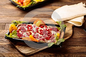 Mutabal with pomegranate seeds and salad served in a dish isolated on wooden table background side view of fastfood