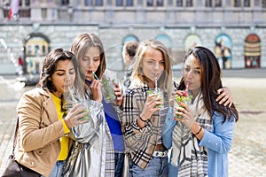 Muti ethnic group of female friends having fun drinking cocktails outdoor in the city in bar restaurant