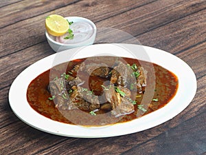 Mutton curry or Lamb curry, spicy and delicious dish served over a rustic wooden background, selective focus