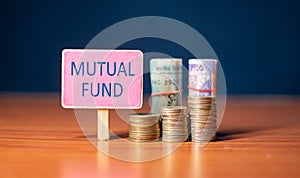 mutual fund sign board with growing coins and stack of money - concept of Investment, savings and wealth creation.