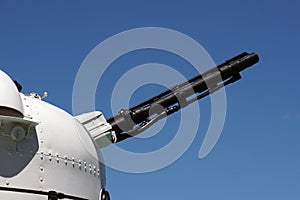 Muzzle barrel of naval ship artillery gun on a blue sky background. copy space, selective focus, narrow depth of field.