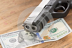 Muzzle of a gun with a 100 dollar bill photo