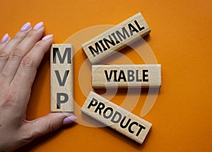 MVP - Most Valuable Player symbol. Wooden cubes with words MVP. Businessman hand. Beautiful orange background. Business and MVP