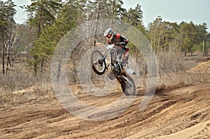 MX racer standing in motion performed a wheelie