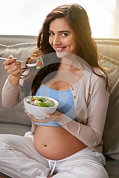 My baby loves it when I eat organic food. a pregnant woman eating a healthy salad at home.