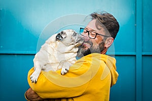 My best friend dog concept with funny scene adult man with beard and pug dog kissing him on the face - people and animals have fun