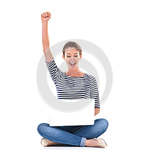 My blog is trending. Studio shot of a young woman sitting cross legged on the floor cheering while using a laptop.