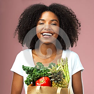 My body deserves the best. Studio shot of an attractive young woman holding a bag full of vegetables against a pink