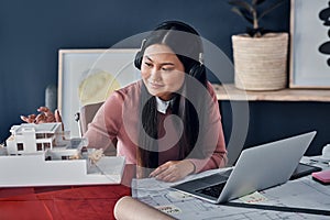 My creativity is right on tune today. an attractive young female architect wearing headphones while working in her