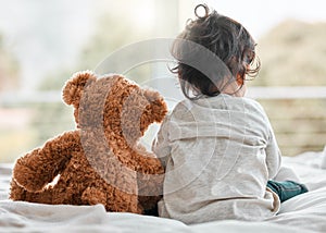 My cuddle buddy forever. Rearview shot of a baby girl sitting at home with her teddybear.