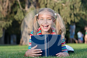 My education came from encyclopedia. Happy little girl read encyclopedia on green grass. Adorable small child smile with