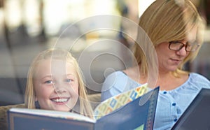 My favorite book. A cute young girl sitting next to her mother while reading a book.