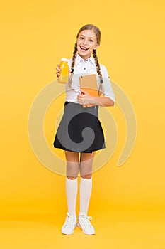 This is my favorite taste. Healthy nutrition. Schoolgirl holding juice bottle on yellow background. Quenching thirst