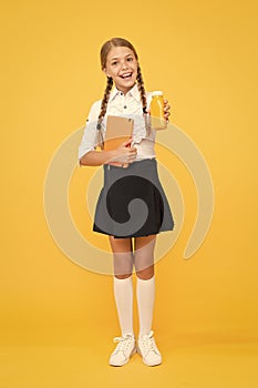 This is my favorite taste. Healthy nutrition. Schoolgirl holding juice bottle on yellow background. Quenching thirst