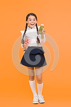 This is my favorite taste. Healthy nutrition. Schoolgirl holding juice bottle on yellow background. Quenching thirst