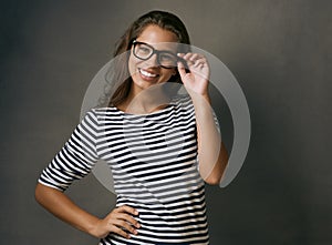 My glasses and I are happy together. Studio shot of an attractive young woman wearing glasses.