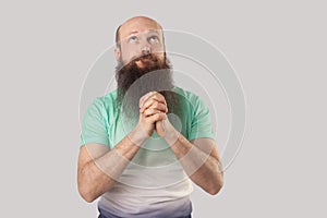 My God please forgive me. Portrait of sad prayer middle aged bald man with long beard standing with palm hands and looking up with