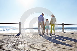My grandparents will always hold my hand. grandparents walking hand in hand with their granddaughter on a promanade.