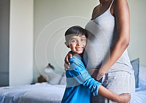 My heart has room for one more. Cropped portrait of an adorable little boy standing against his mothers pregnant belly.