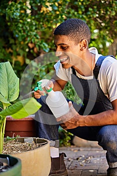 My idea of self-care is spending time with my plants. Cropped shot of a handsome young man crouched in his garden and