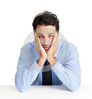 My job stinks. A demoralized young businessman leaning on a table with his head in his hands against a white background.