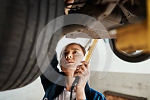 My knowledge of cars allows me to diagnose problems much quicker. a female mechanic working under a lifted car.