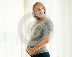 This is my last trimester. Shot of a beautiful woman holding on to her pregnant belly.