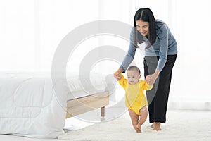 My little girl takes first steps. family happy little baby learning to walk with mother help at home