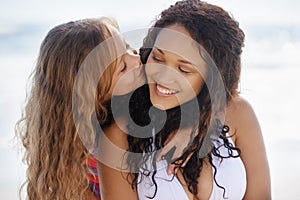 My mom is the best. A little girl kissing her mother on the cheek at the beach.