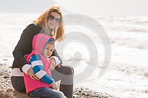 My mother and five year old daughter sit on beach and looked at turning frame