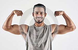 My muscles are my best clothes. Studio portrait of a muscular young man flexing his biceps against a white background.