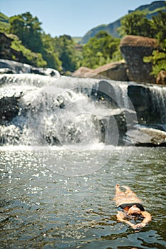 This is my paradise. Full length shot of an unrecognizable woman swimming in a stream alone during a day outdoors.