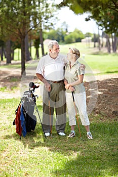 My partner in life and ... golf. A happily married senior couple standing together and smiling during a game of golf.