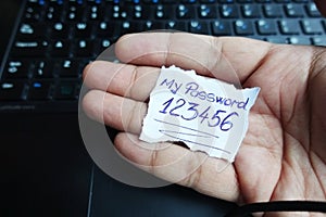 My password 123456 on paper note held by man hand above computer keyboard photo