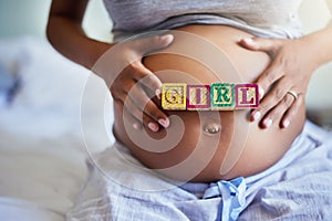 My princess is almost here. a pregnant woman with wooden blocks on her belly that spell the word girl.