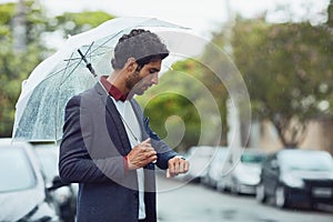 My ride should be here any minute. Cropped shot of a handsome young businessman on his morning commute in the rain.